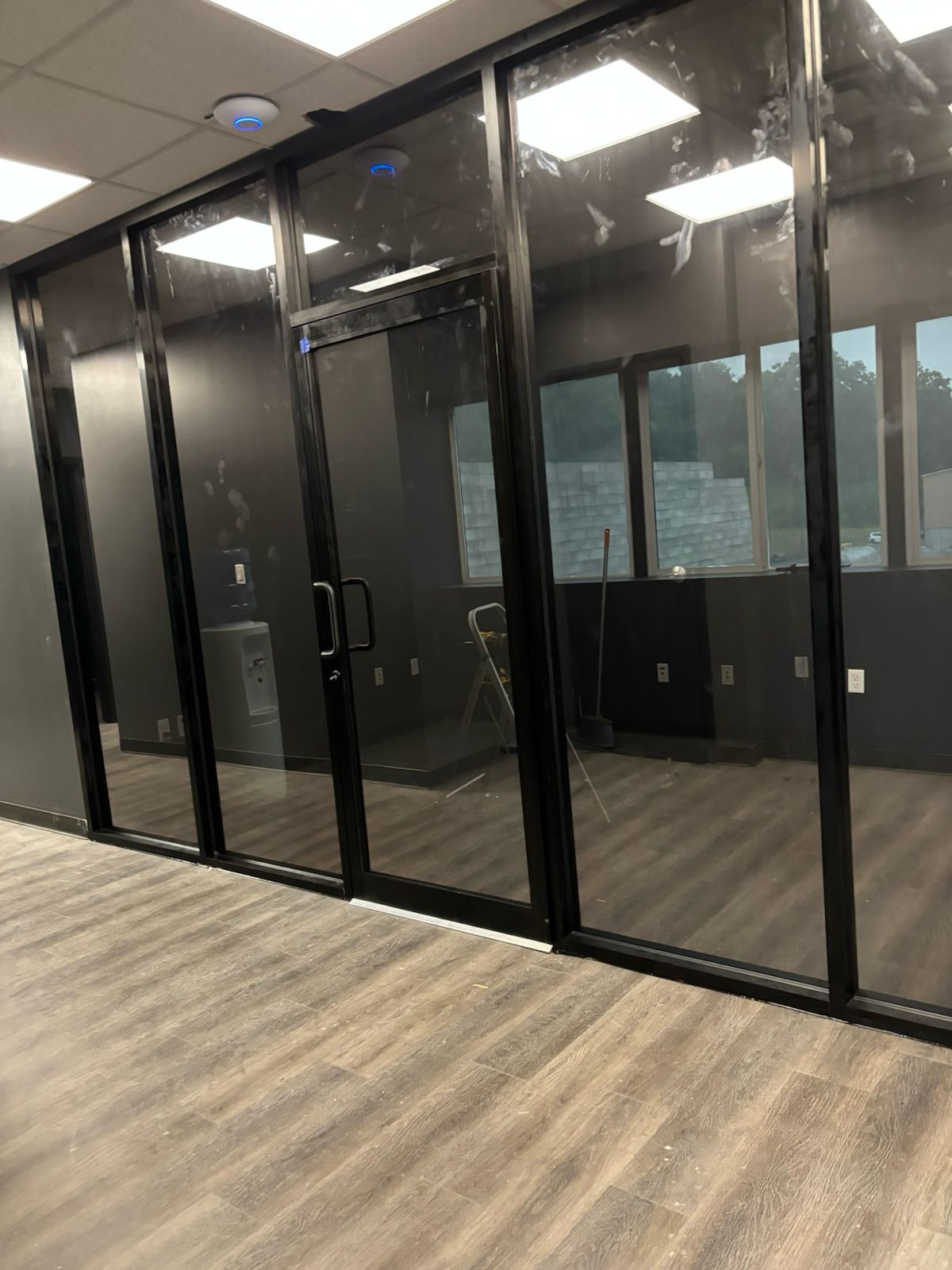 Interior glass partition wall with black aluminum frames in commercial office space
